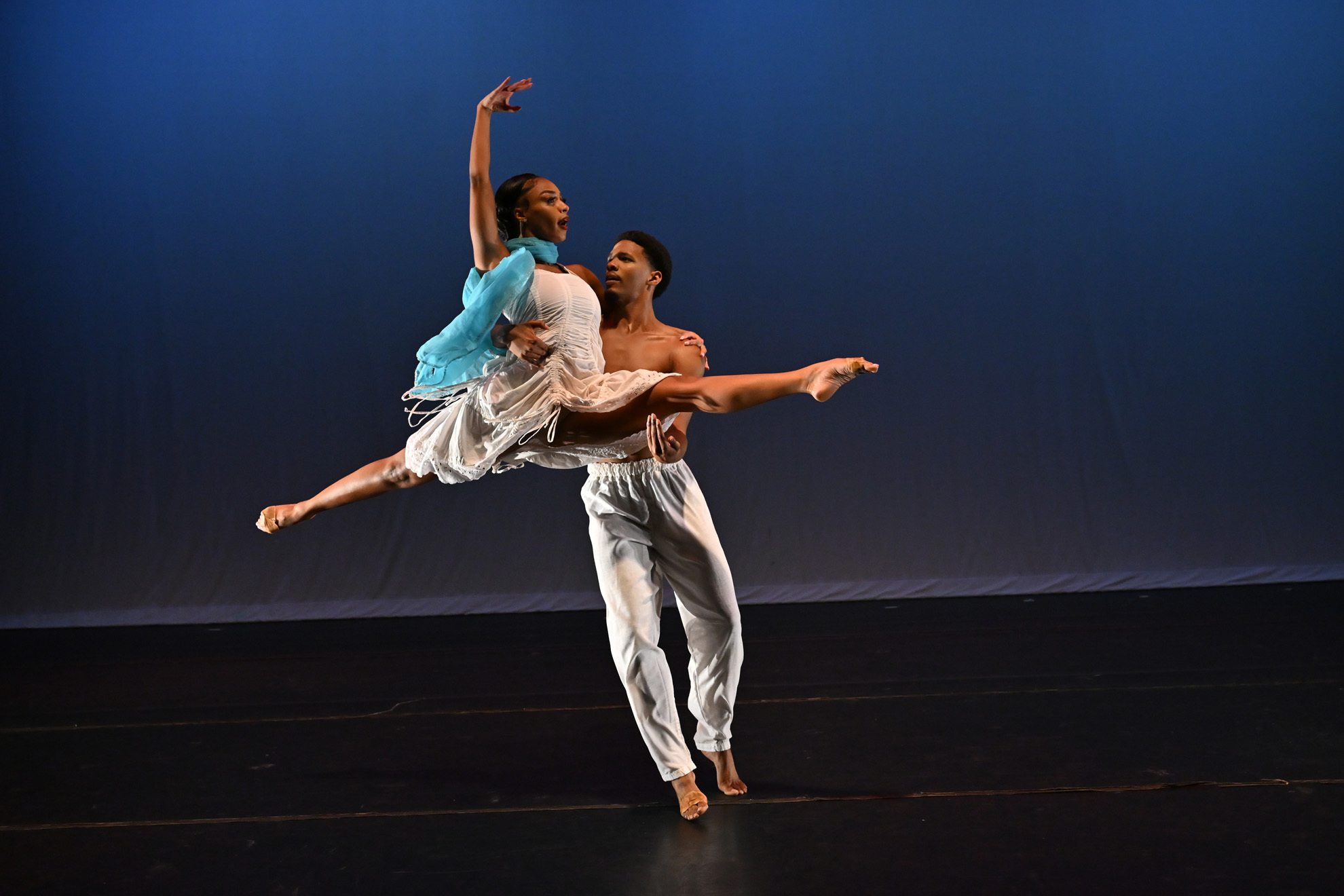 Cleo Parker Robinson Dance ensemble members Corey Boatner and Caeli Blake performing Orfeu Negro. Boatner lifts Blake, who is doing the splits with her right arm overhead.