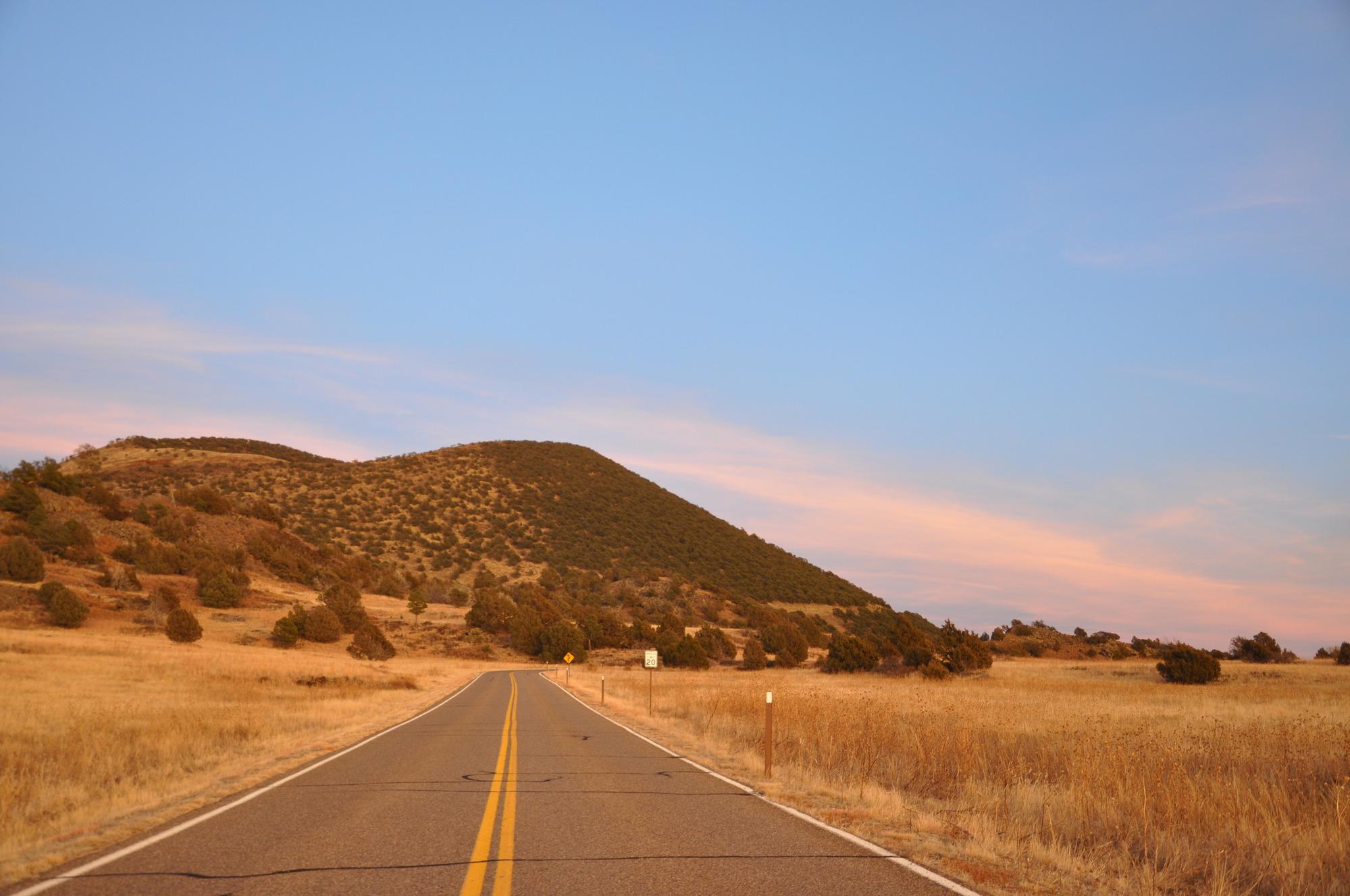 A rural road leads to a cinder cone volcano