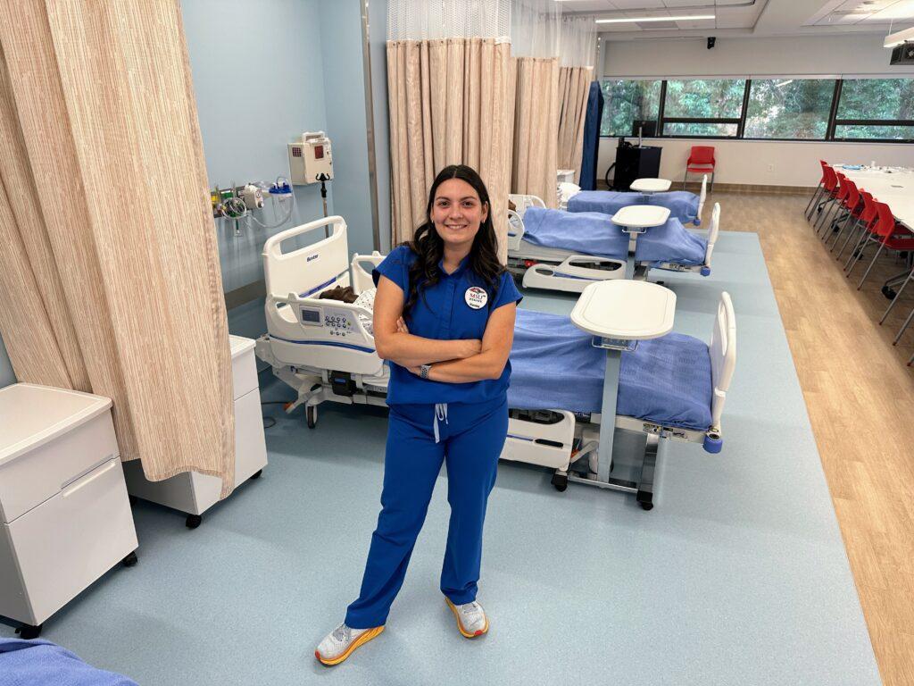 A nursing student stands in a laboratory.