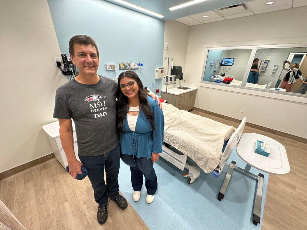 A nursing student stands with her father.