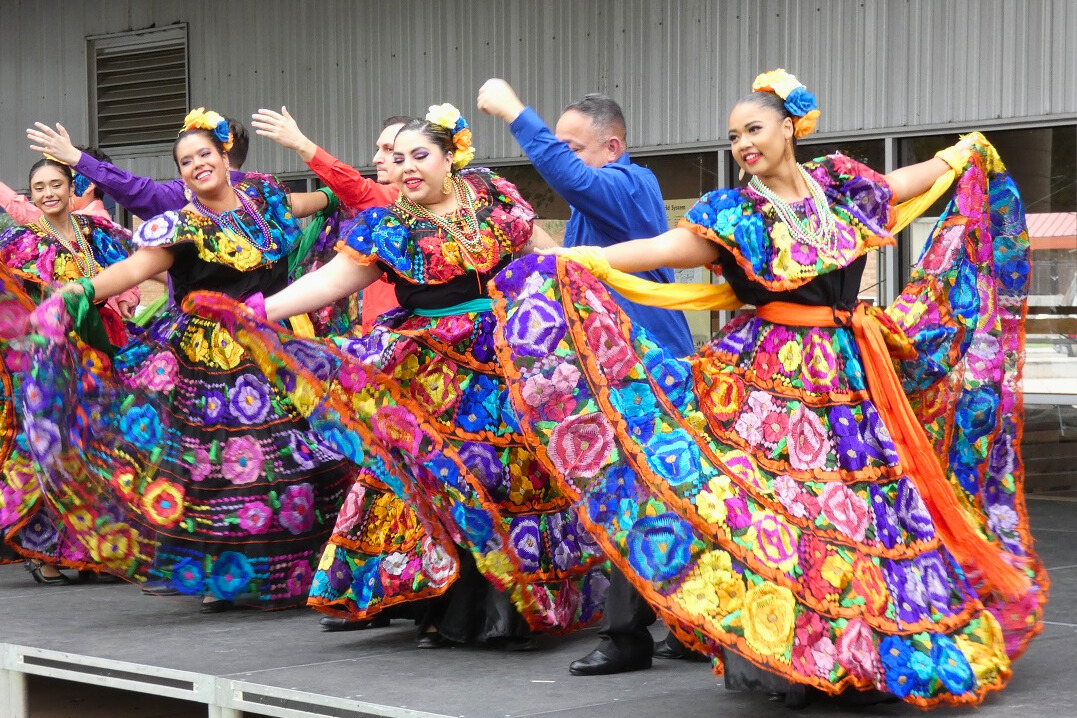 Women and men in colorful outfits dance