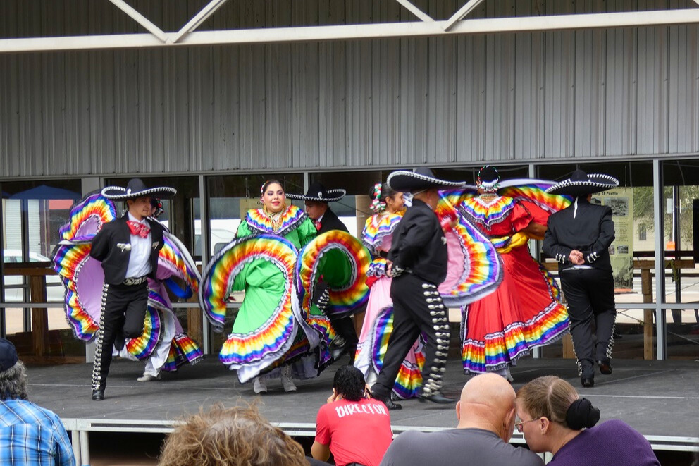 Women and men in colorful outfits dance