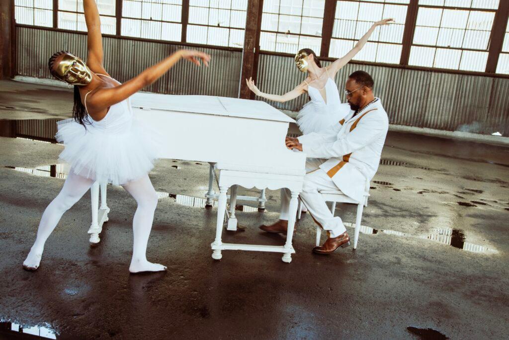 RZA playing the piano while ballet dancers perform around him.