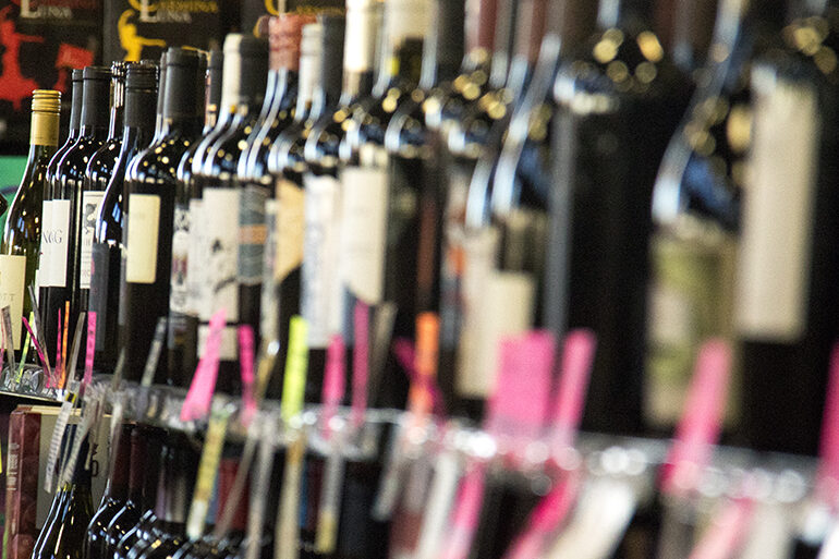 Man removes bottle from liquor store wine display.