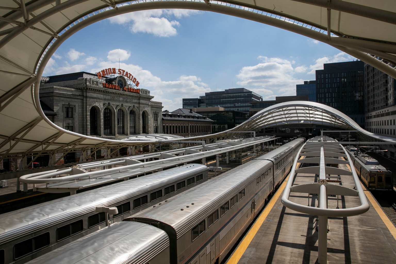 A row of trains sits in a station with a Union Station sign hovering over it.