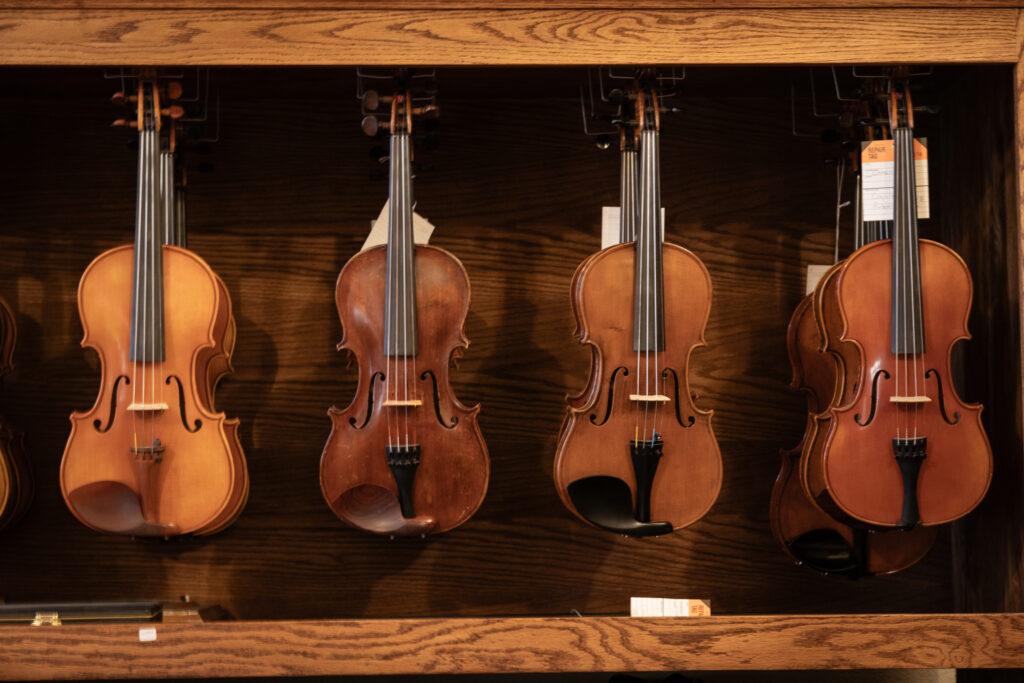 Finished violins hang in a cabinet