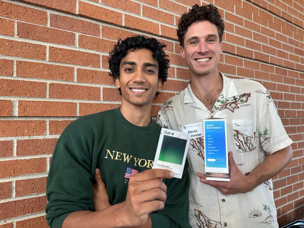 Two men hold boxes of dietary supplements.