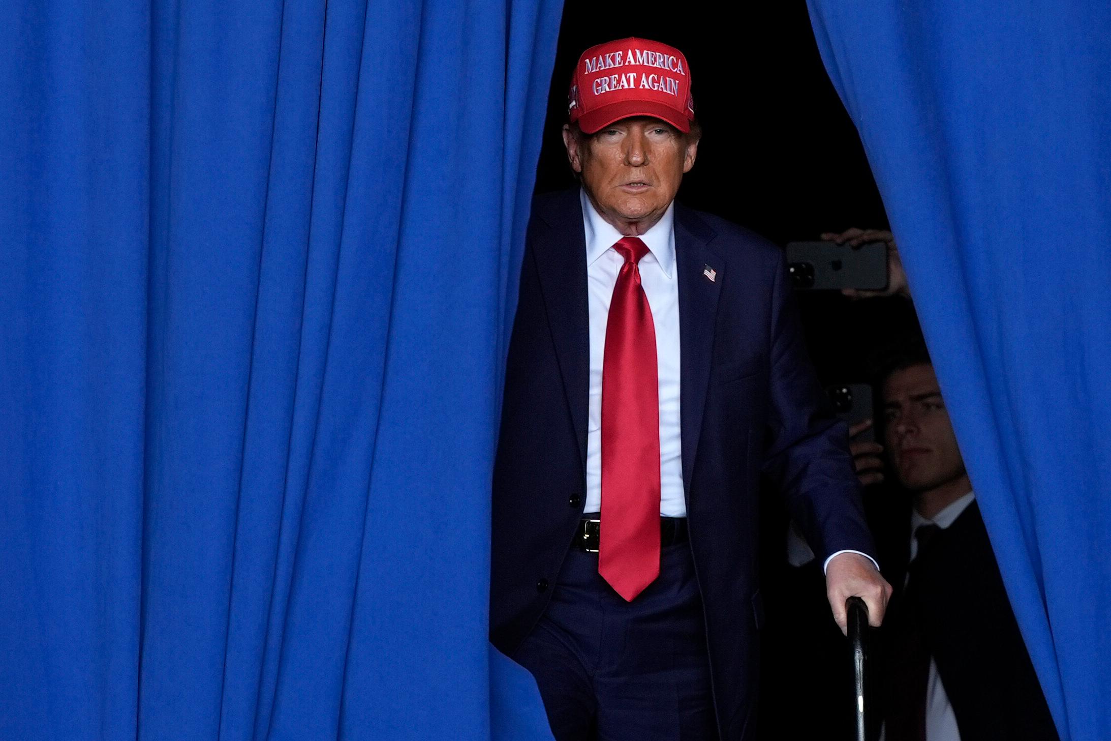 Former president Donald Trump steps from behind a blue curtain to take the stage at a campaign rally in Wisconsin.