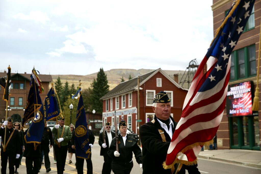 An American Legion chapter marches down a street holding flags