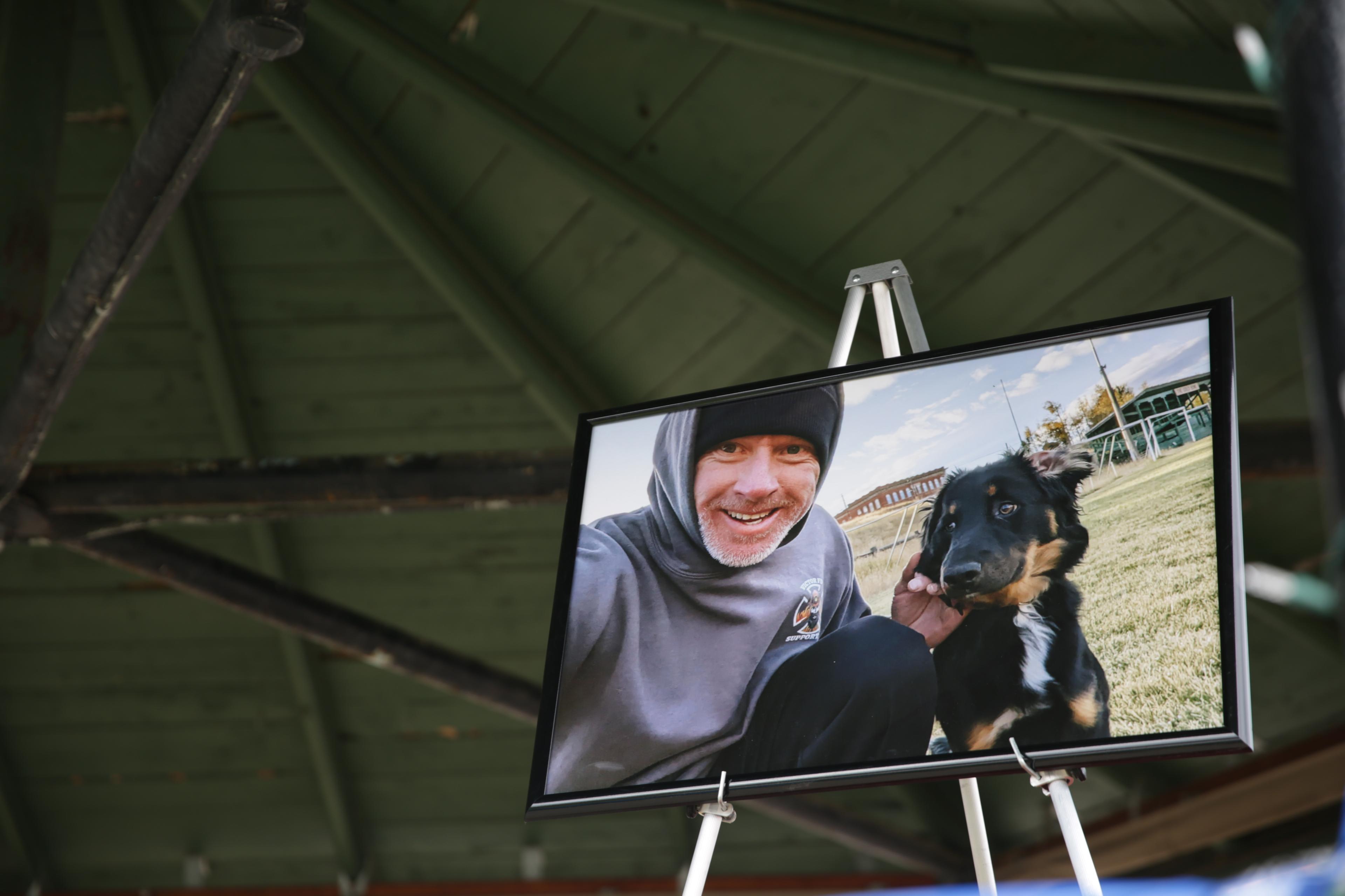 A photo of a man wearing a hoodie and beanie holding a dog