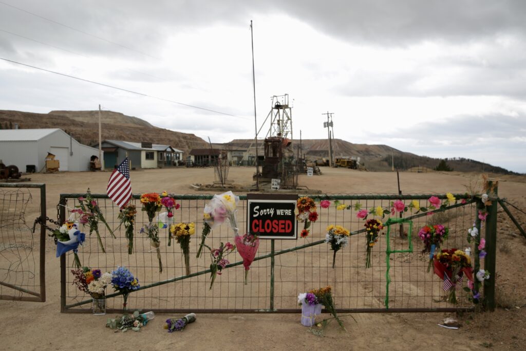 Mining site with a gate marking the site closed. The gate is covered with memorial flowers