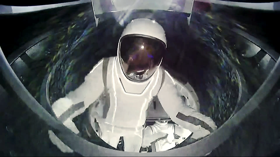 Astronaut Sarah Gillis is pictured wearing a spacesuit and helmet as she took a spacewalk outside the Crew Dragon capsule.