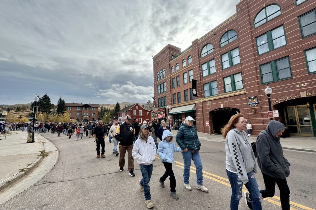 A crowd walks up a street during a memorial procession