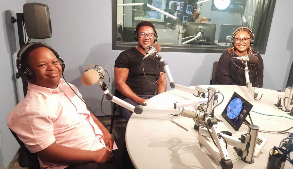 Photo shows Jeremiah Daniels with his father and mother sitting at microphones in a CPR news studio.