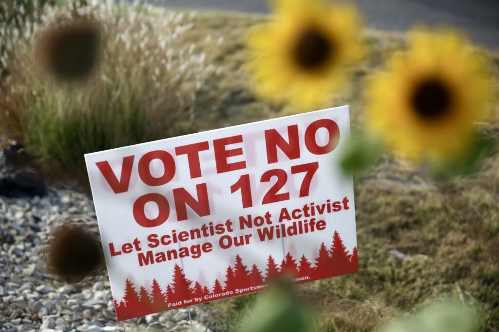 A sign amidst sunflowers reads &quot;Vote no on 127&quot;