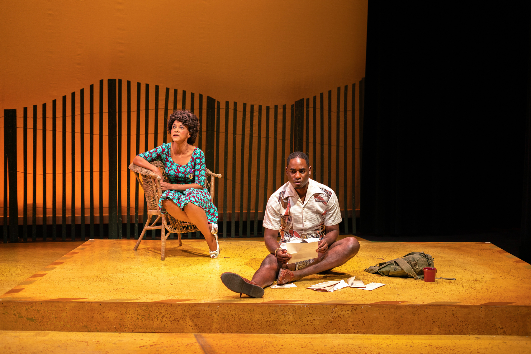 Two actors on a sparse set -- one yellow riser and a fence in the background -- for the premiere production of "Stockade" at Local Theater Company in Boulder.