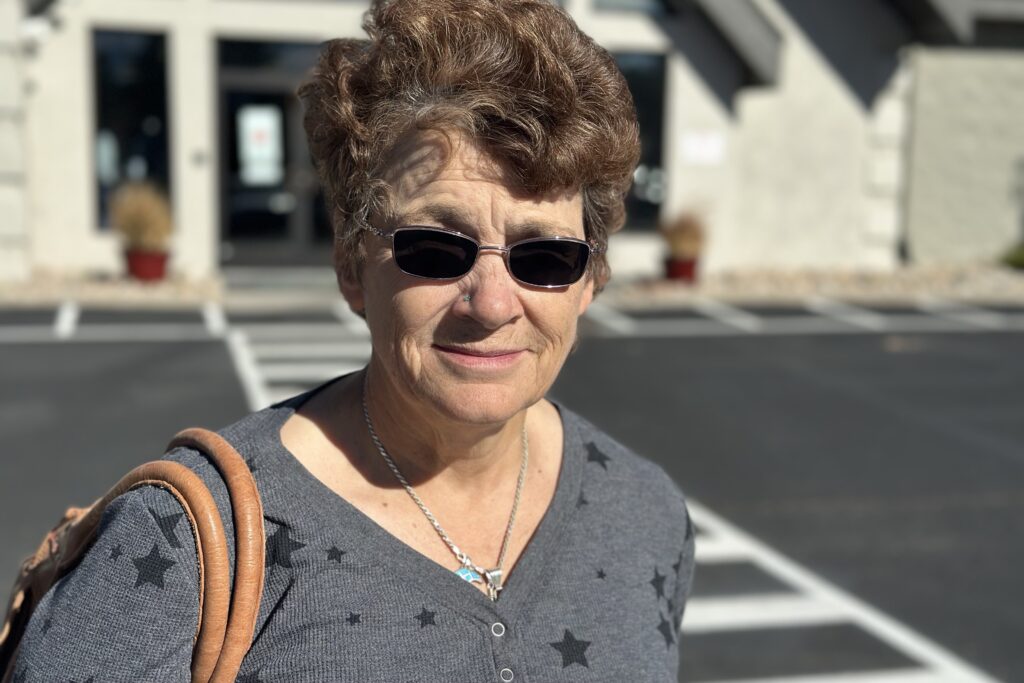 A woman with dark sunglasses stands outside a church