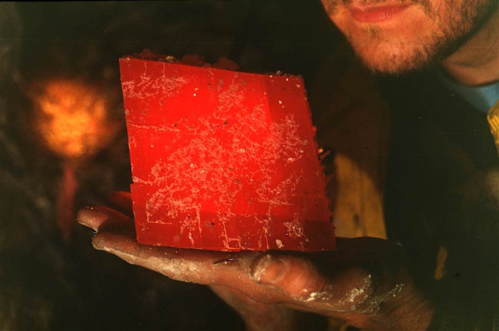 A bright red, large crystal in a man's hand