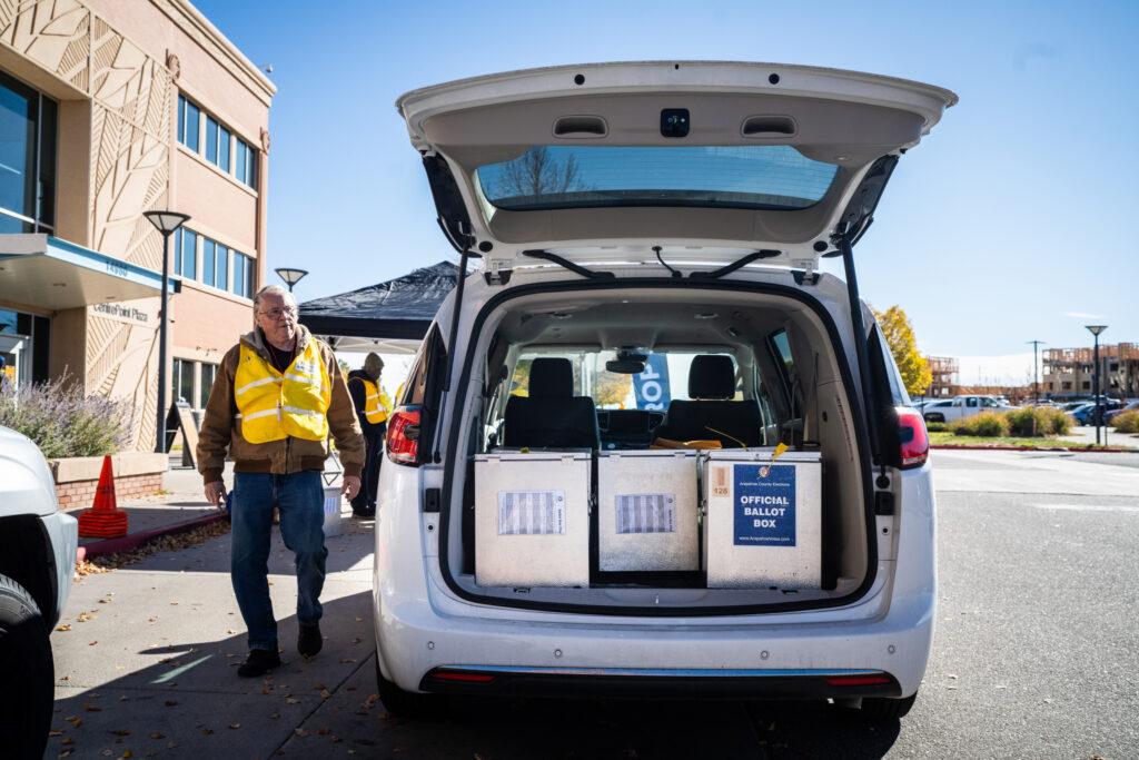 Election Day workers load full ballot boxes into a van