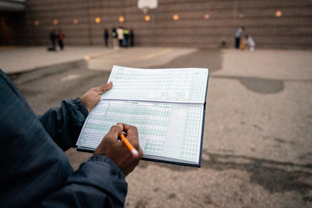 Cricket coach writes down score in a notebook