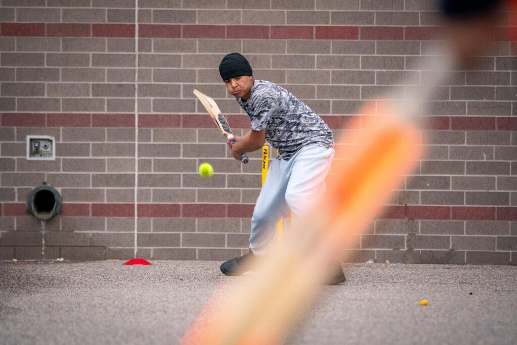 Cricket player swings bat at ball