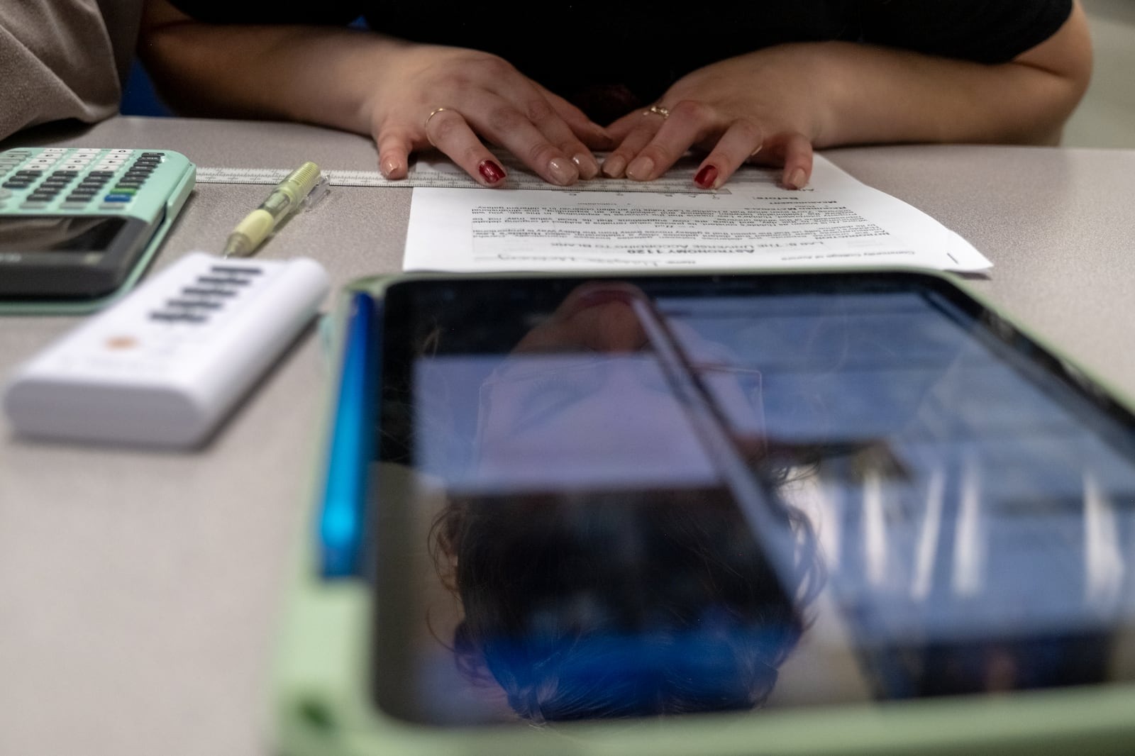 A student sitting at a table with a paper and tablet in front of them.