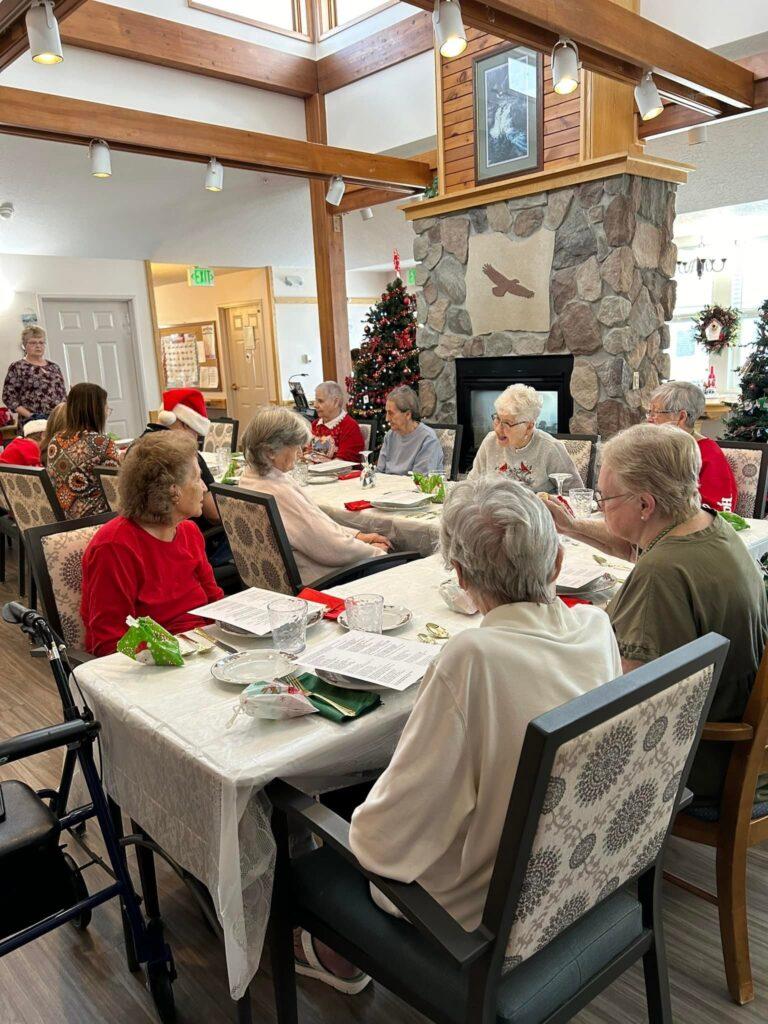 Residents sit at tables for a Christmas holiday gathering in the common area of the Eagle Crest Assisted Living facility in Rangely, Colo. A fireplace and Christmas trees can be seen in the background.