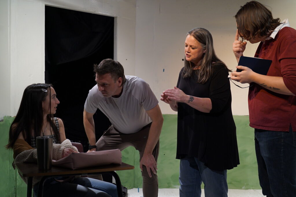 A team of performers engaged in a scene around a table during a rehearsal for The Thanksgiving Play at Springs Ensemble Theatre.