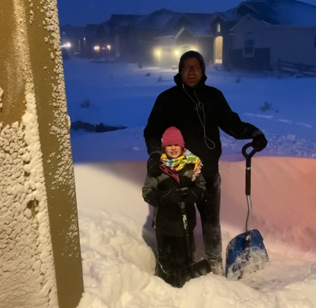 Emily and her dad stand outside on a snow night.