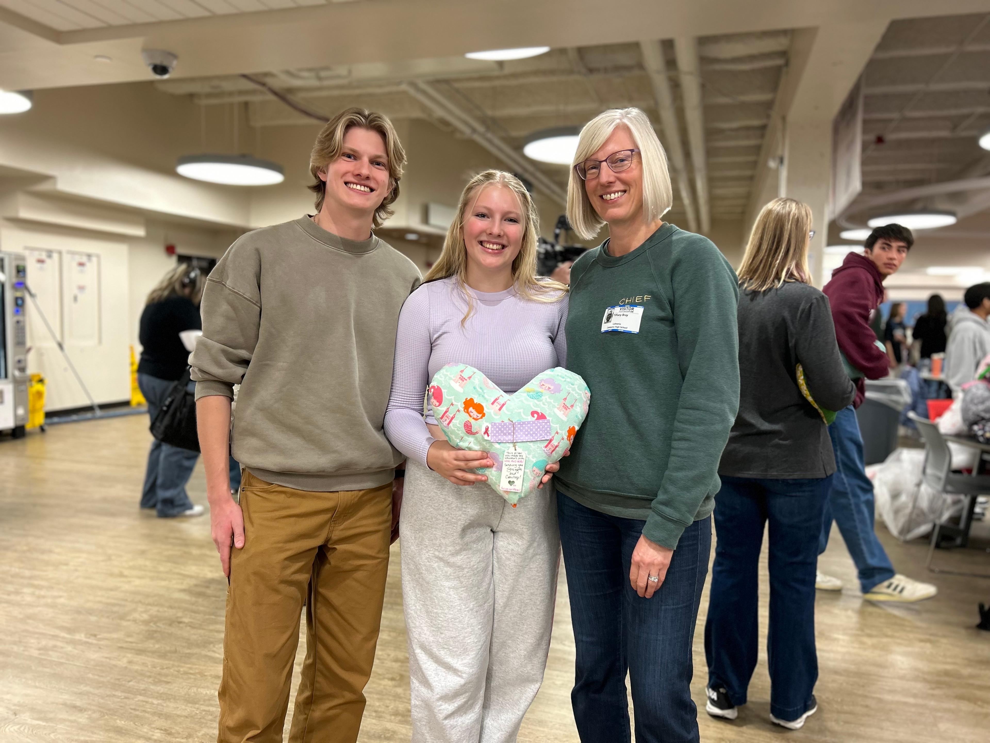 Austin and Aubrey Bray, both students at Centaurus high school, stand with their mom, Tiffany Bray, holding a heart shaped pillow.