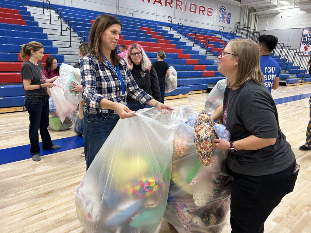 Two faculty members fill bags with heart shaped pillows for donation.