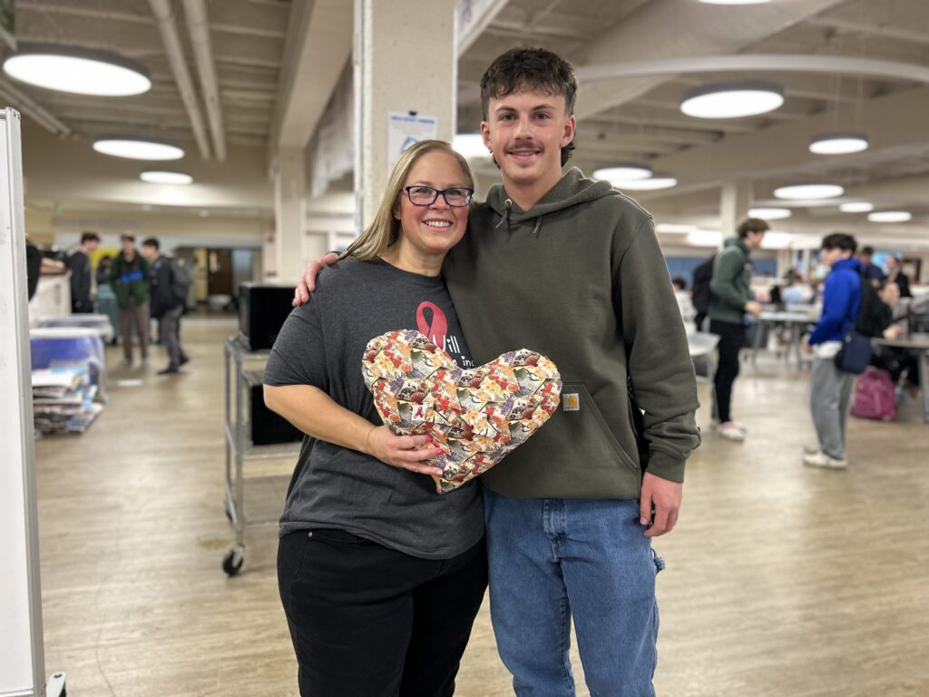 Billy Plampin, a Centaurus stands with his mom, Lindsay, as she holds a heart shaped pillow.