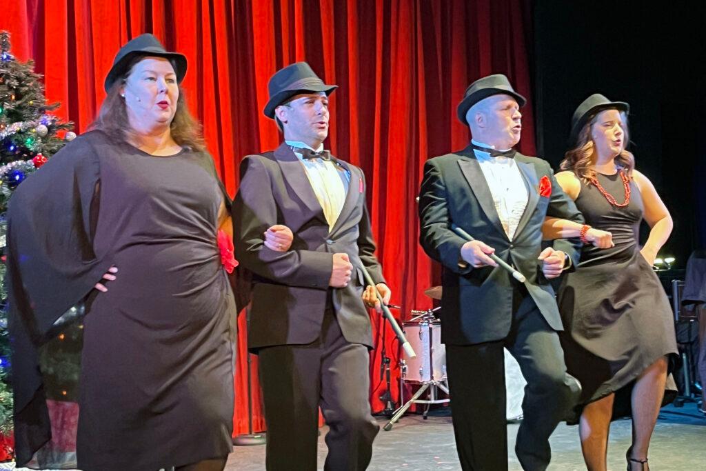 Four performers in tuxedos, cocktail dresses, and hats on stage at Longmont Theatre for &quot;Christmas My Way,&quot; celebrating the Rat Pack style.