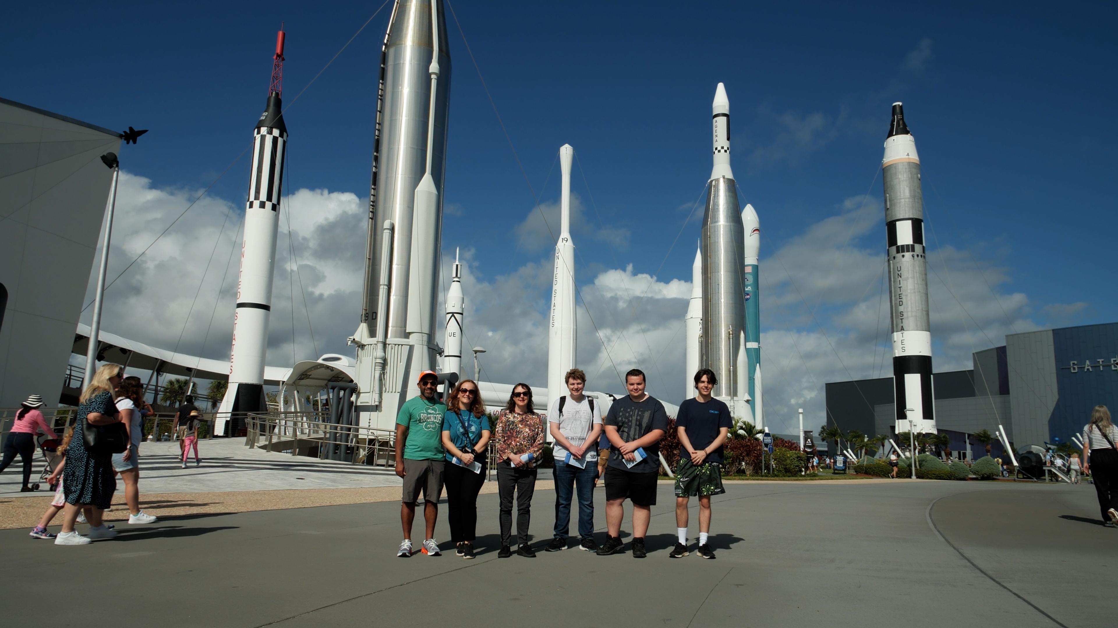 Students and faculty of UCCS/PPSC stand in front of several rockets of various sizes and models at NASA's Kennedy Space Center.