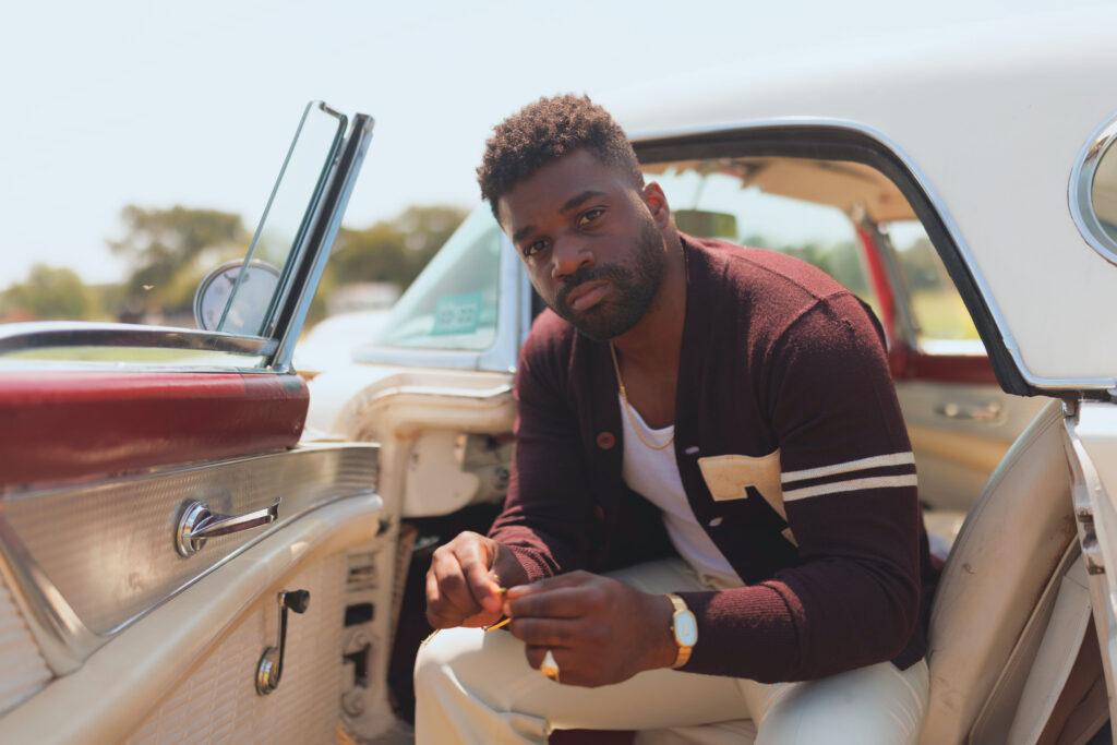 man wearing sweater sitting in front seat of open car