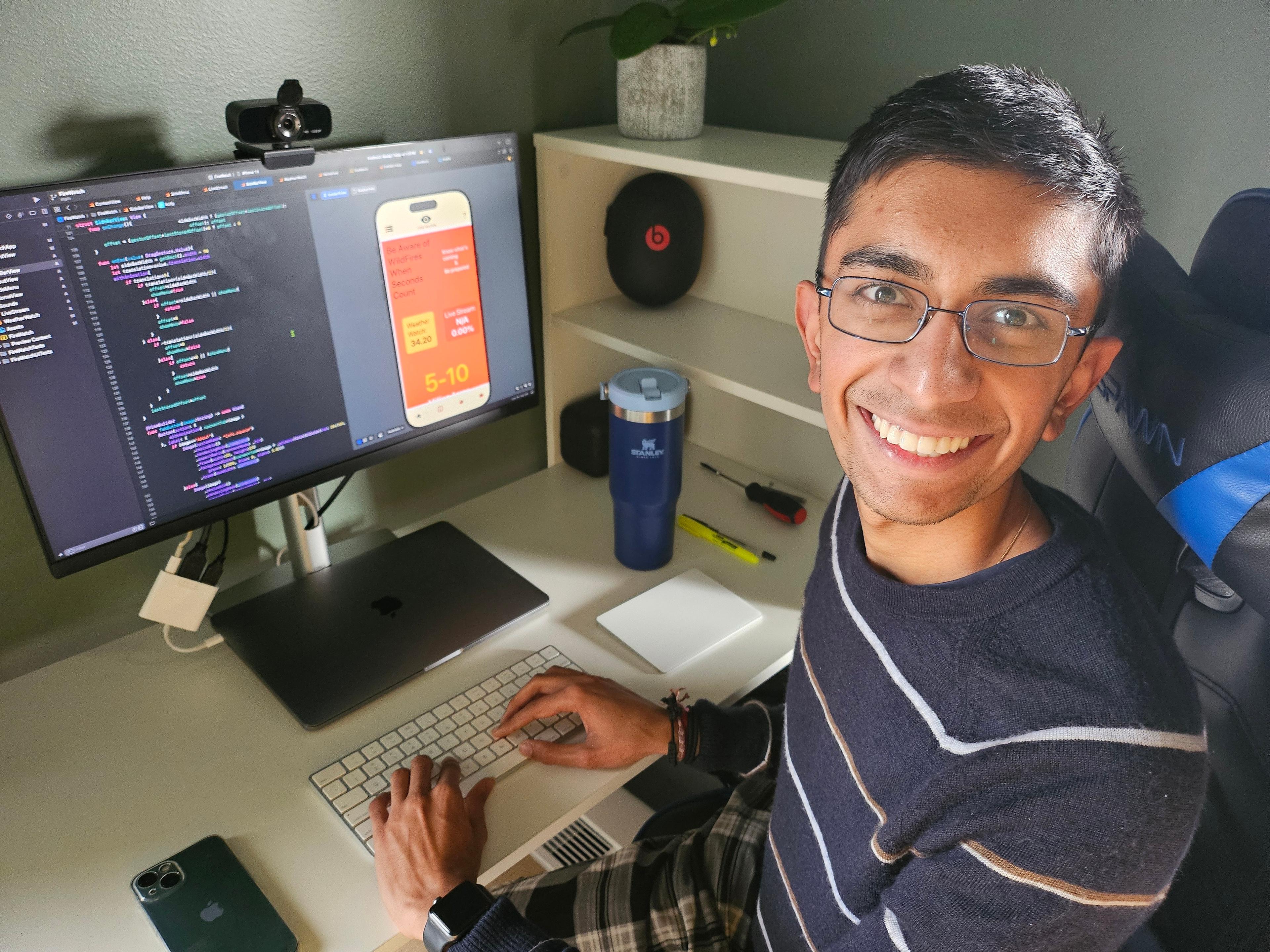 Aadi Sobti sitting at a desk with his app FireWatch on the cumputer screen