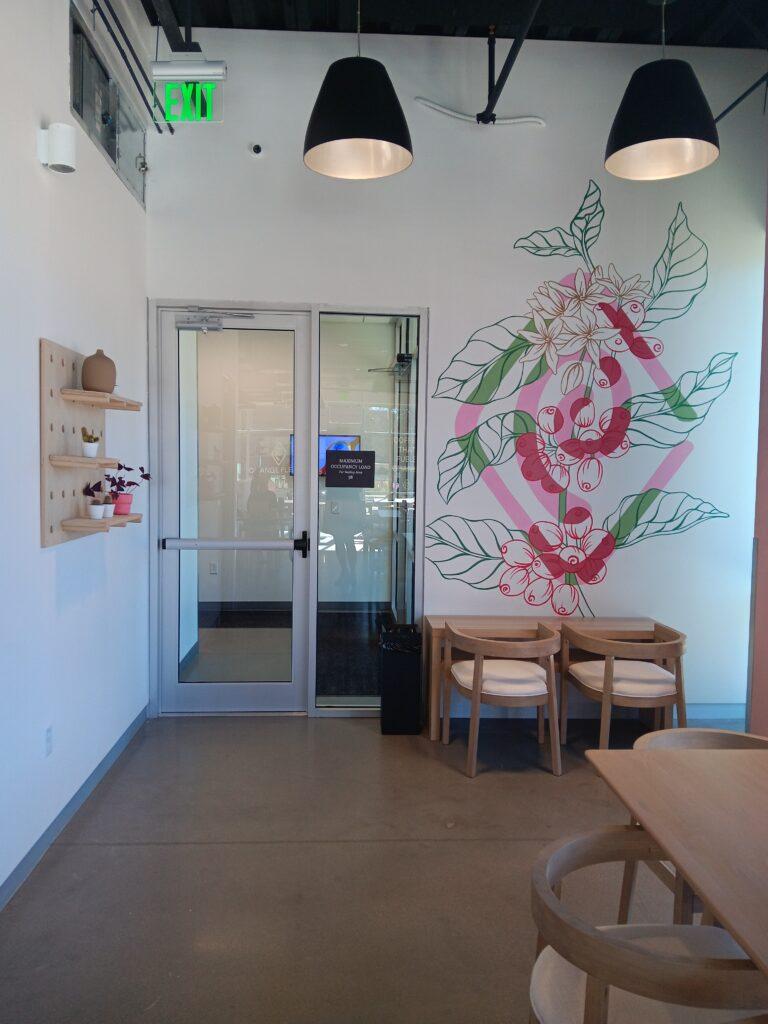 part of the inside of a cafe with a painting of a large flower on the far wall