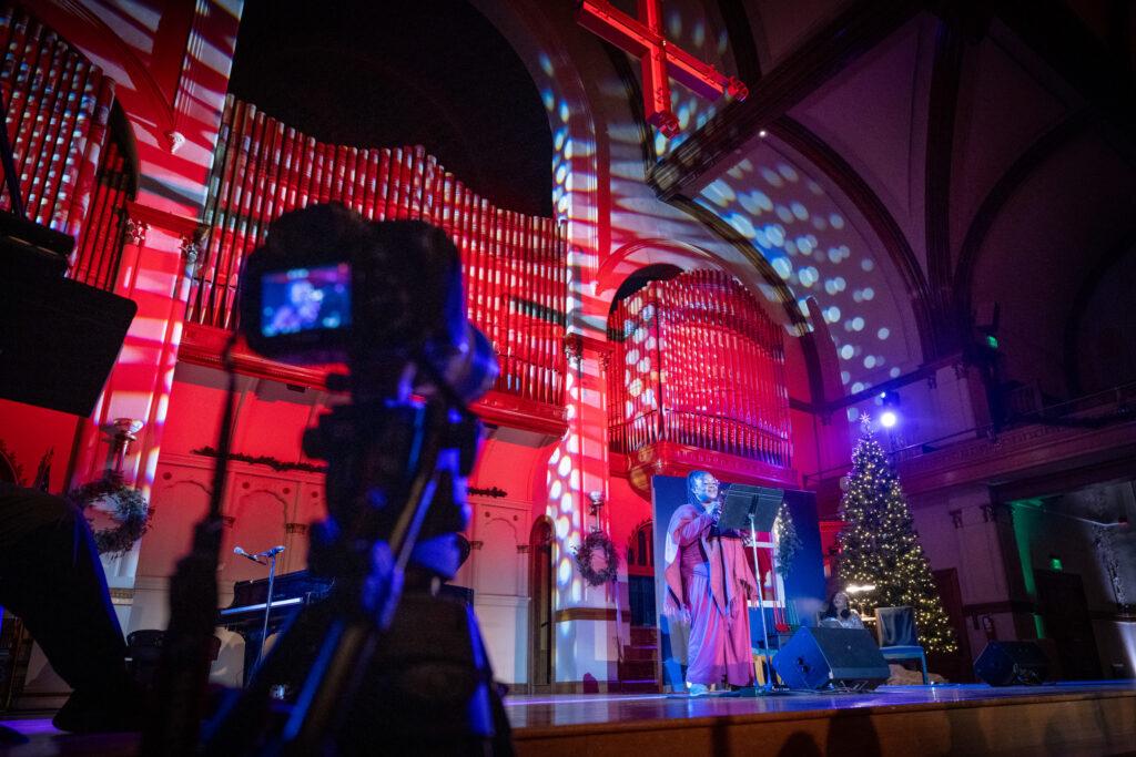 Poet Confidence Omenai on stage at the Colorado Matters Holiday Extravaganza