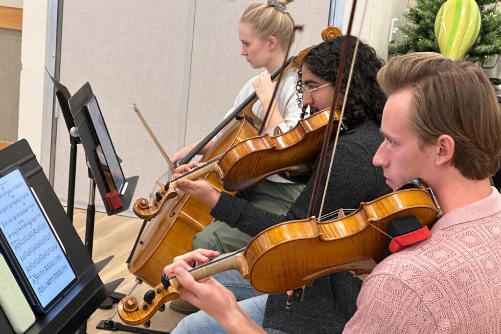 Two violinists and a cellist with Boulder Opera perform from sheet music in front of them.