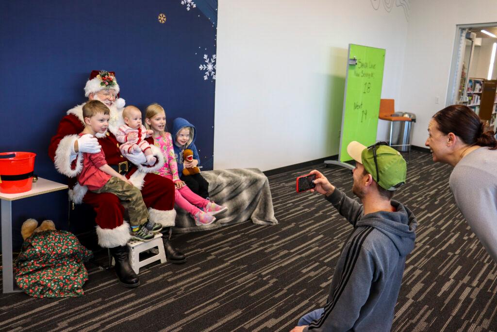 Parents take photos of their children sitting on a Santa's lap at the Jefferson County Library.