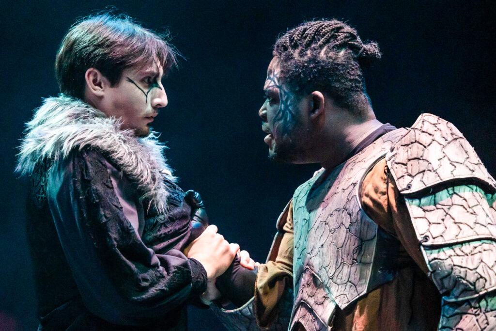 Two students in costume play in MacBeth with the student at right grabbing the student at left by the front of their shirt.