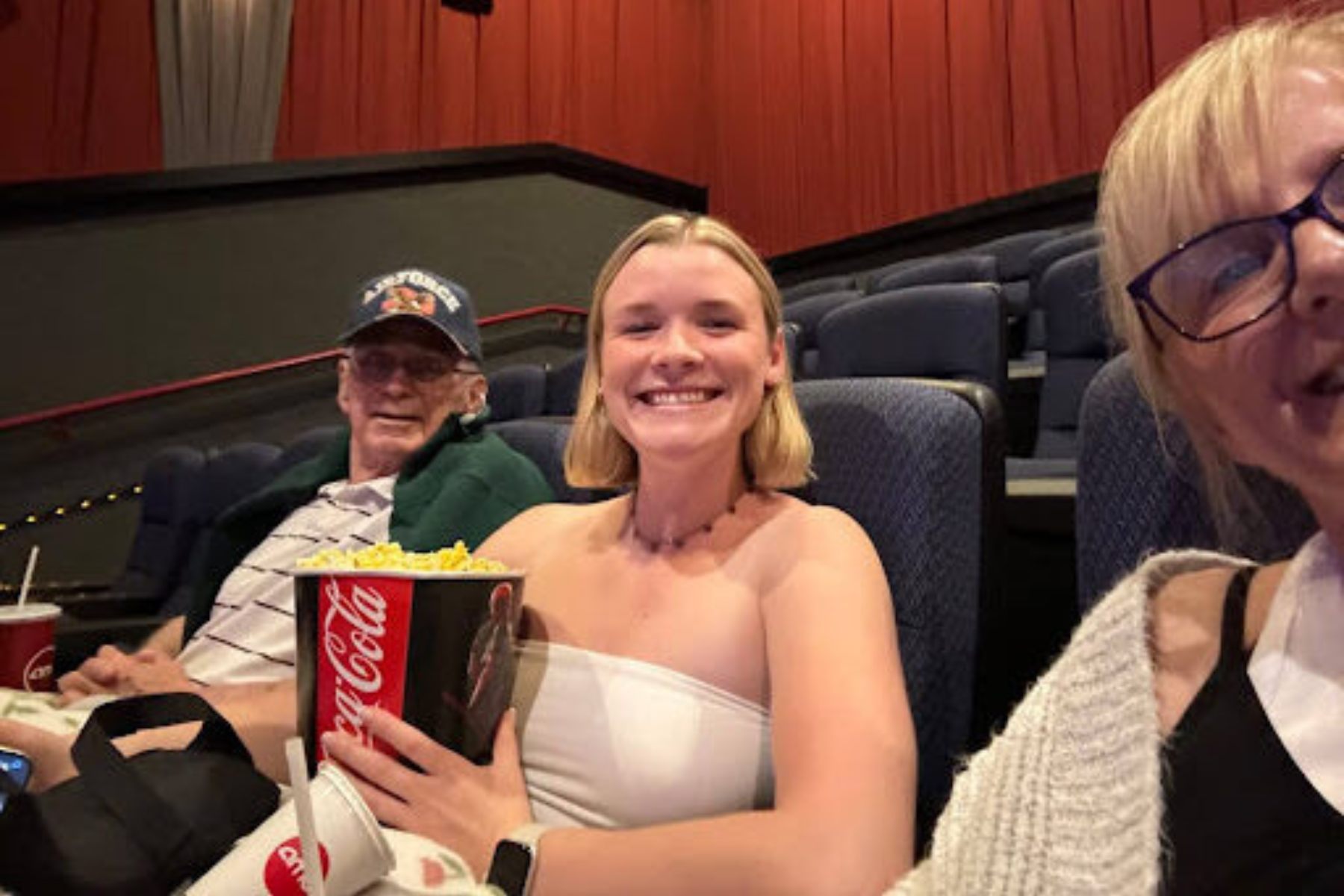 Photo shows a father, his granddaughter, and daughter in seats at a theater awaiting a performance.