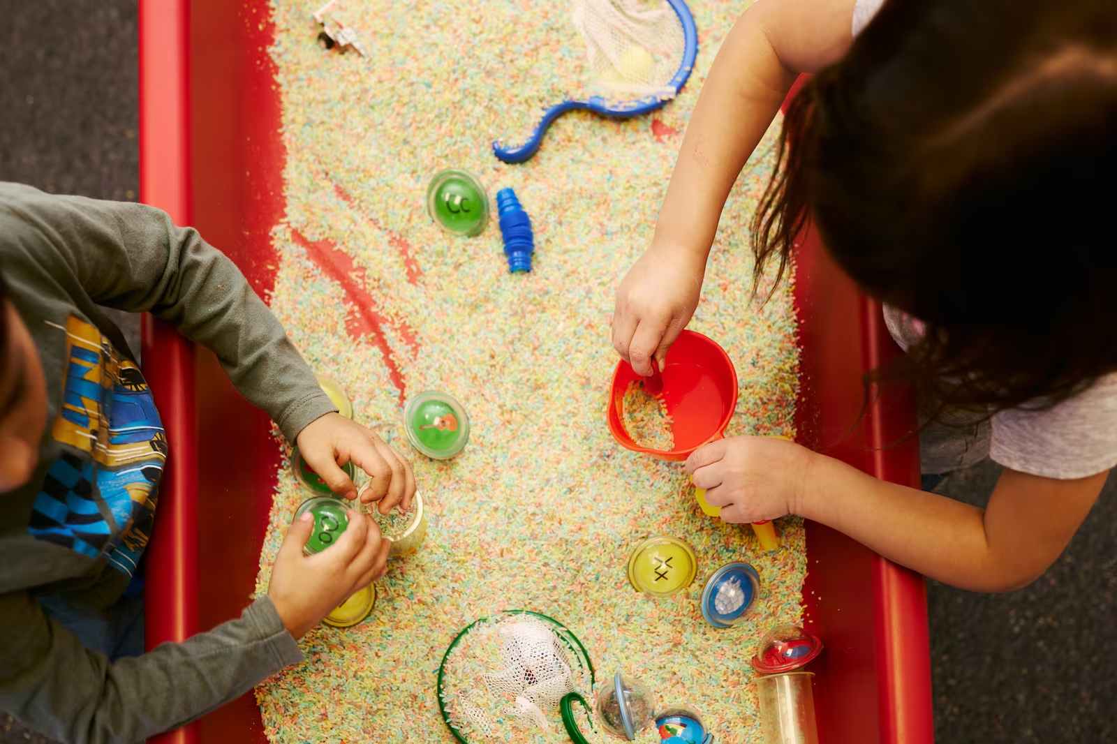 Camera faces down on two kids playing in a sandbox