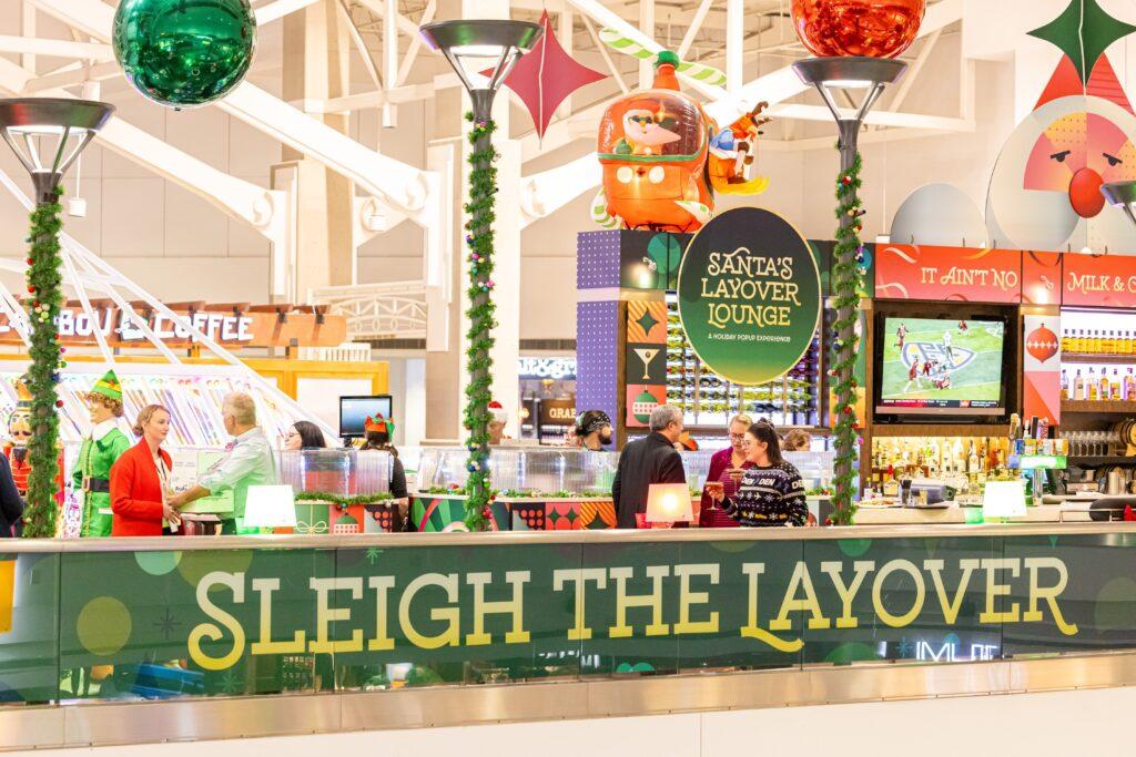 Photo shows people chatting inside Santa's Layover Lounge at DIA.