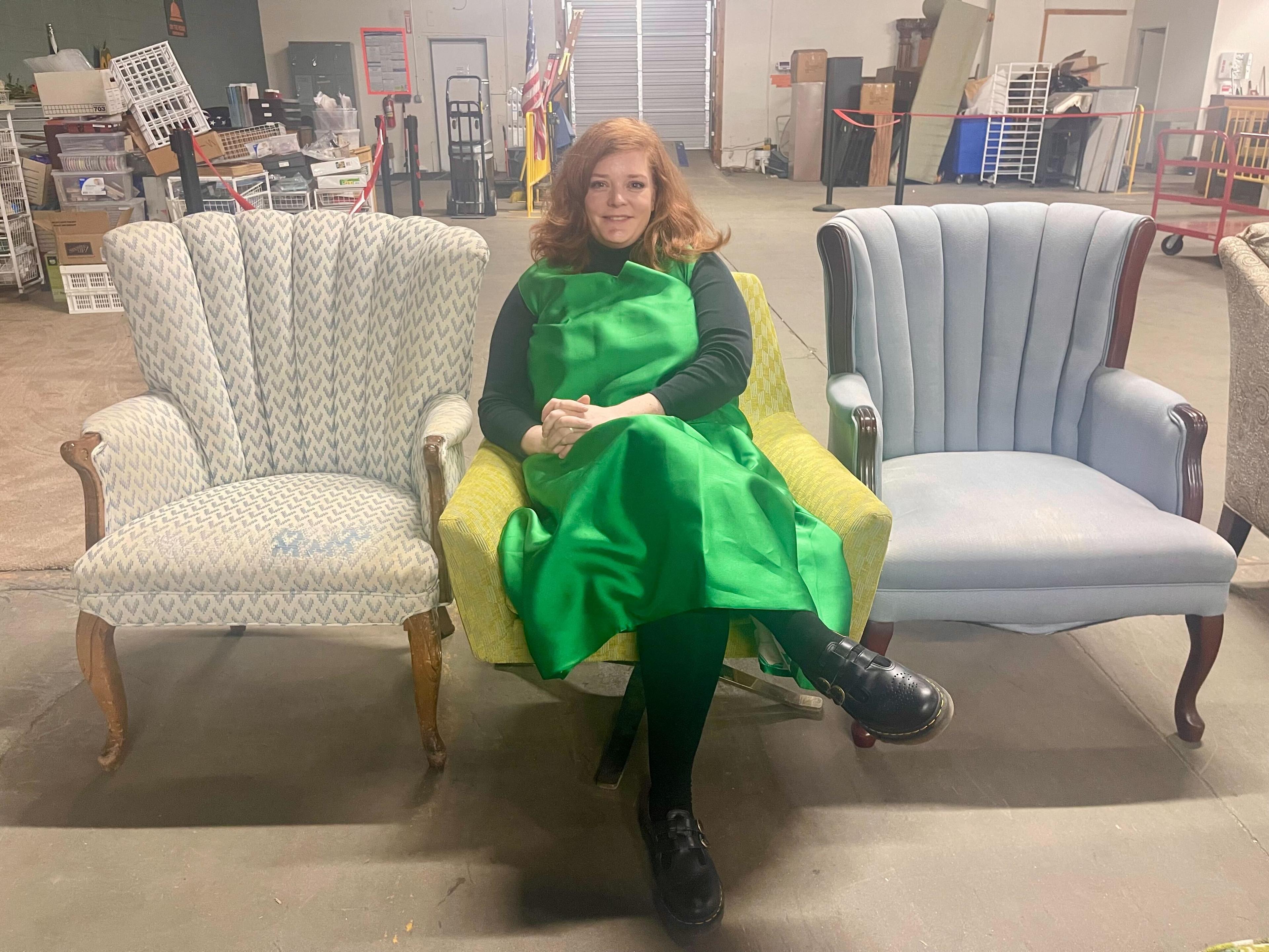 Woman sits in donated chair-- flanked by other chairs that will go to families in need.