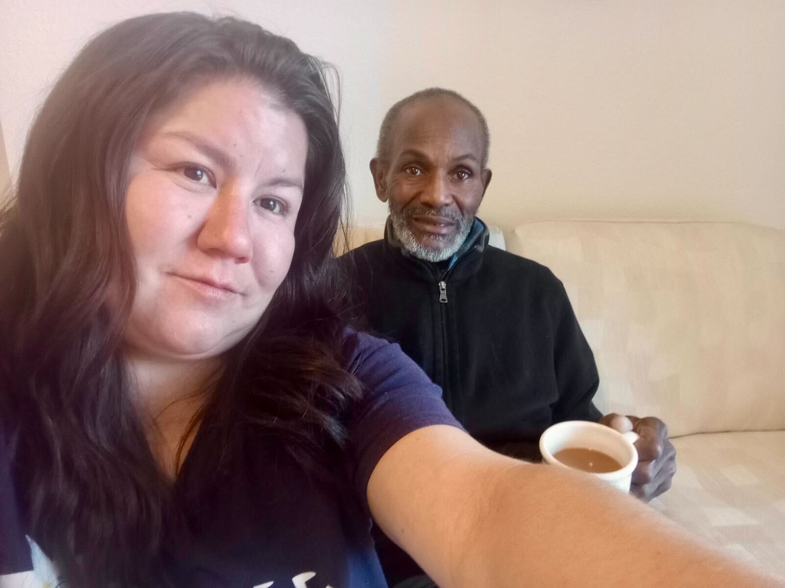 Couple takes a selfie while sitting on a crisp, cream-colored couch.