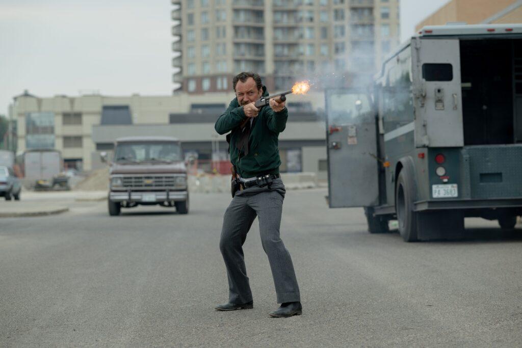 Photo shows actor Jude Law in a movie clip firing a gun in a street at a suspect as FBI agent Terry Husk in the movie &quot;The Order.&quot;