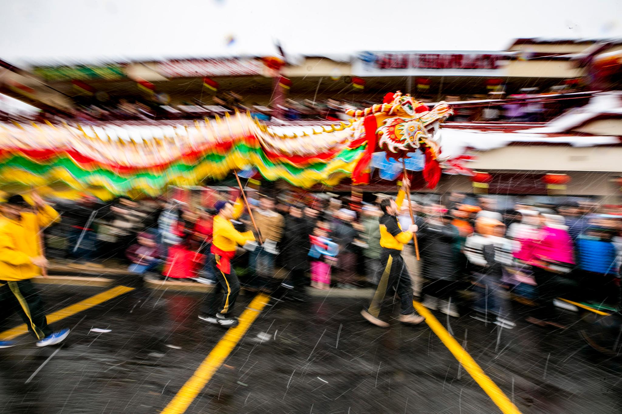 Shaolin Hung Mei Kung Fu students run a yellow green and red dragon during a Lunar New Year celebration.