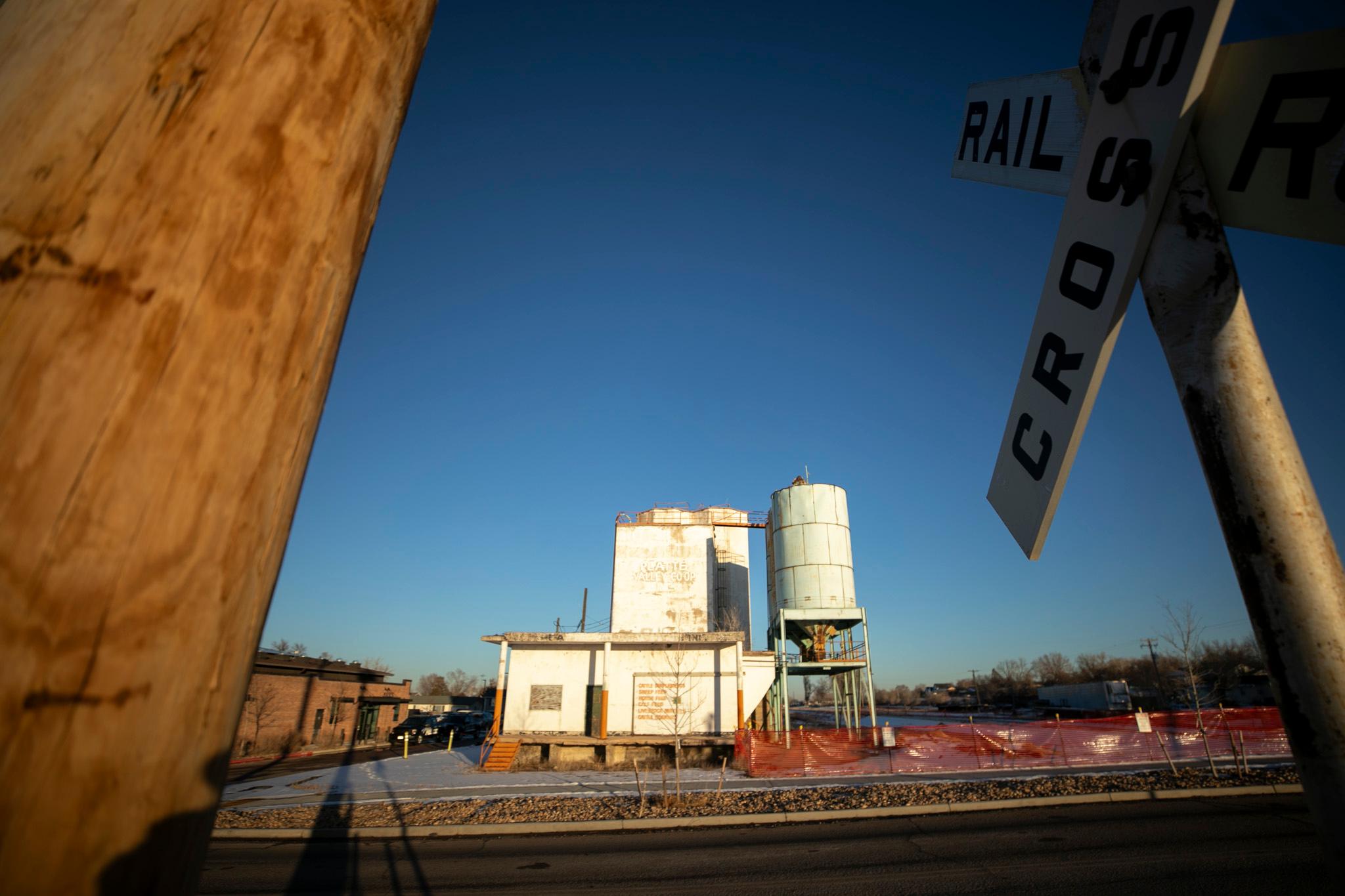 A white building sits unused in a big lot amid blue sky and framed by two poles.