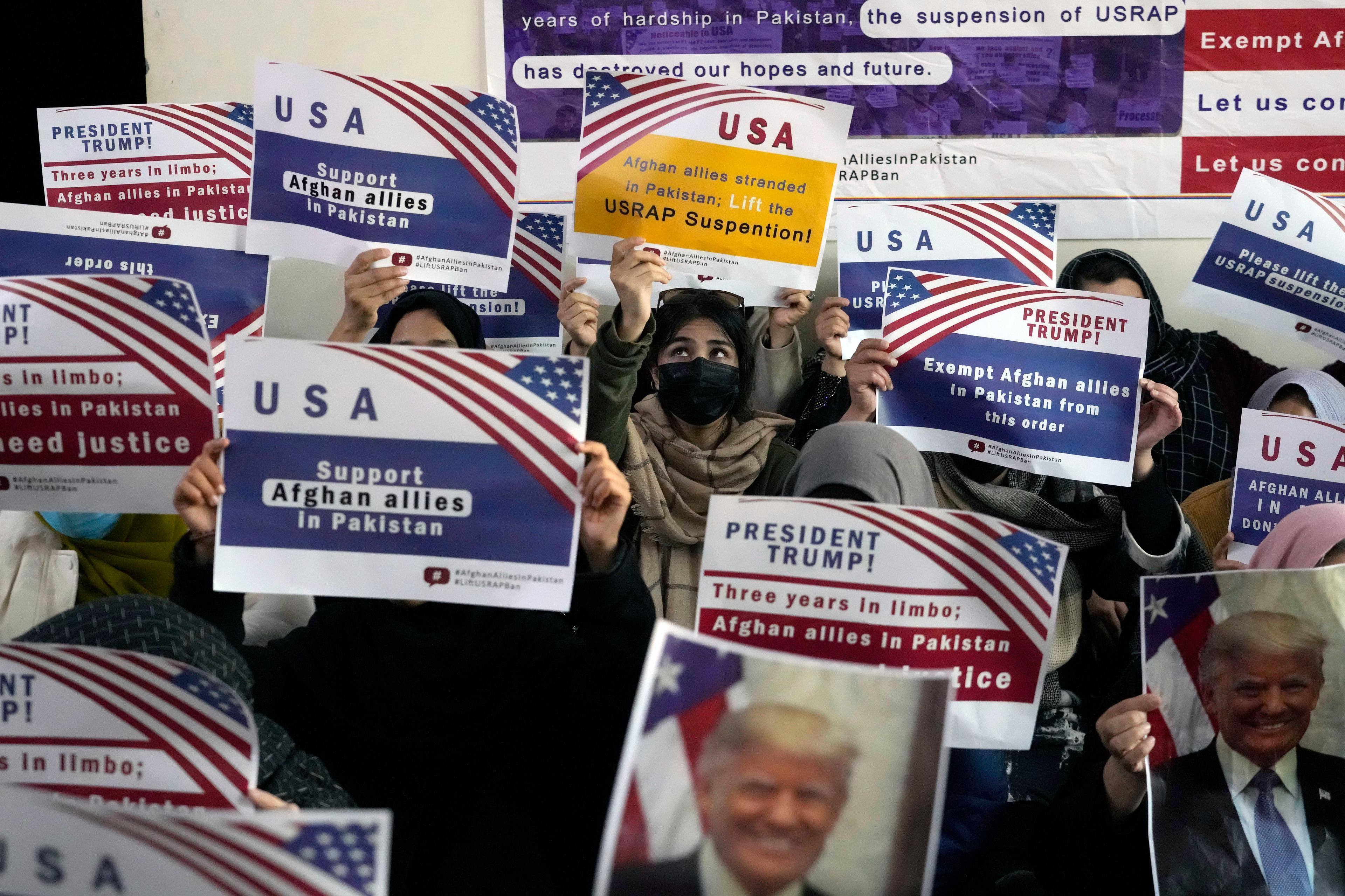 Pakistan Afghan Refugees hold signs discussing paused U.S. programs